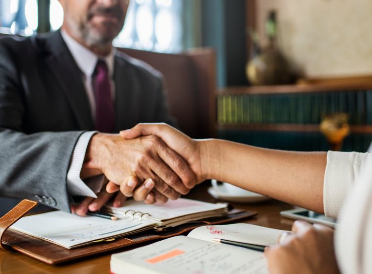 Attorney shaking hands with a client across a desk